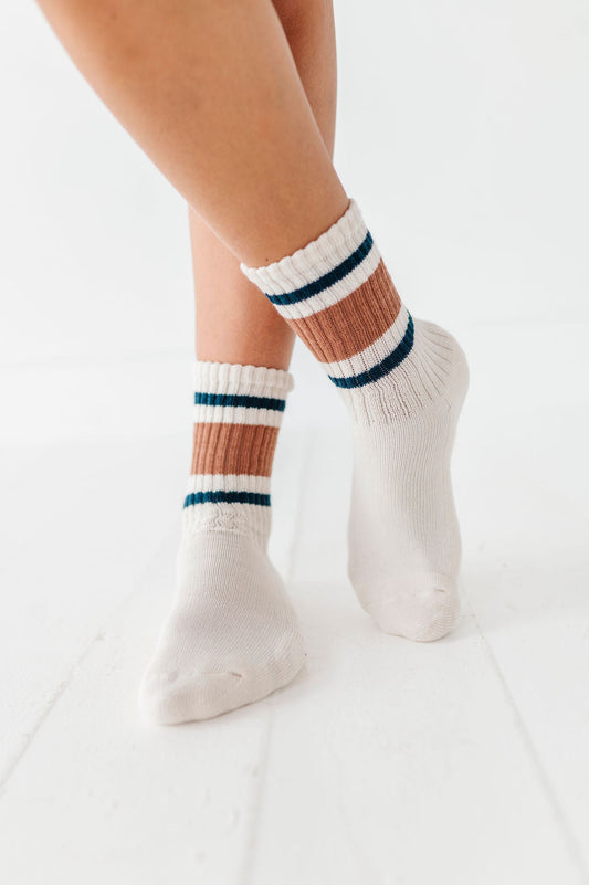 White socks with multicolor stripes worn by a person on a white background