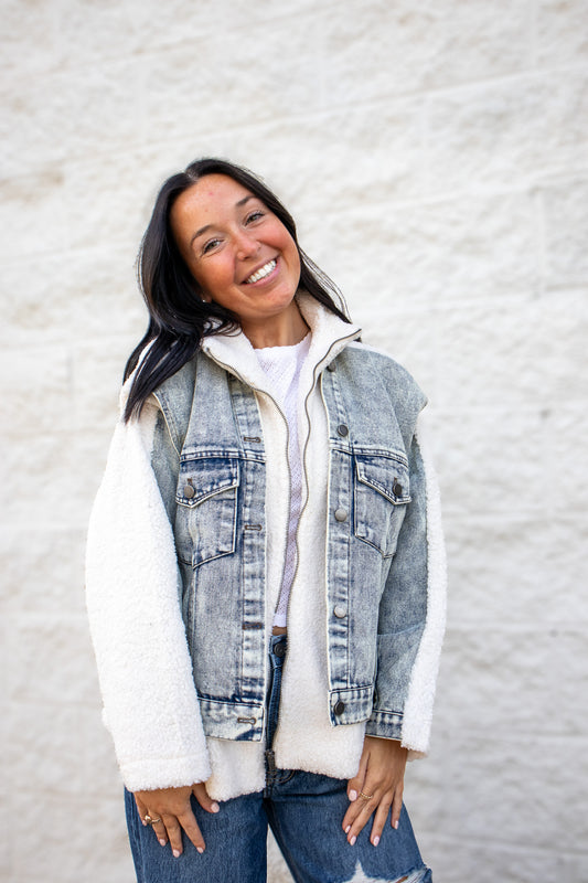 Woman wearing a denim vest over a white shirt with a light gray background