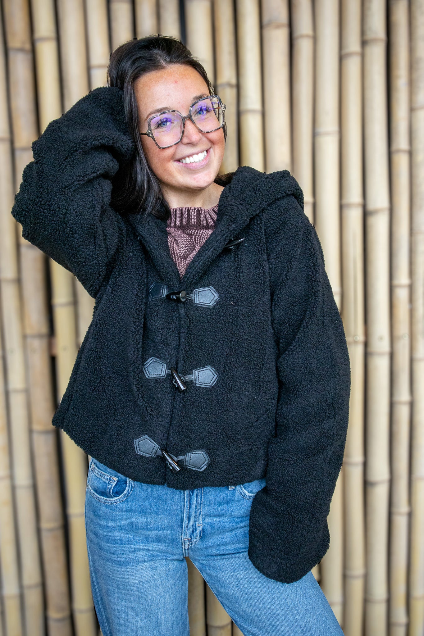 Woman wearing a black coat with a textured wall background
