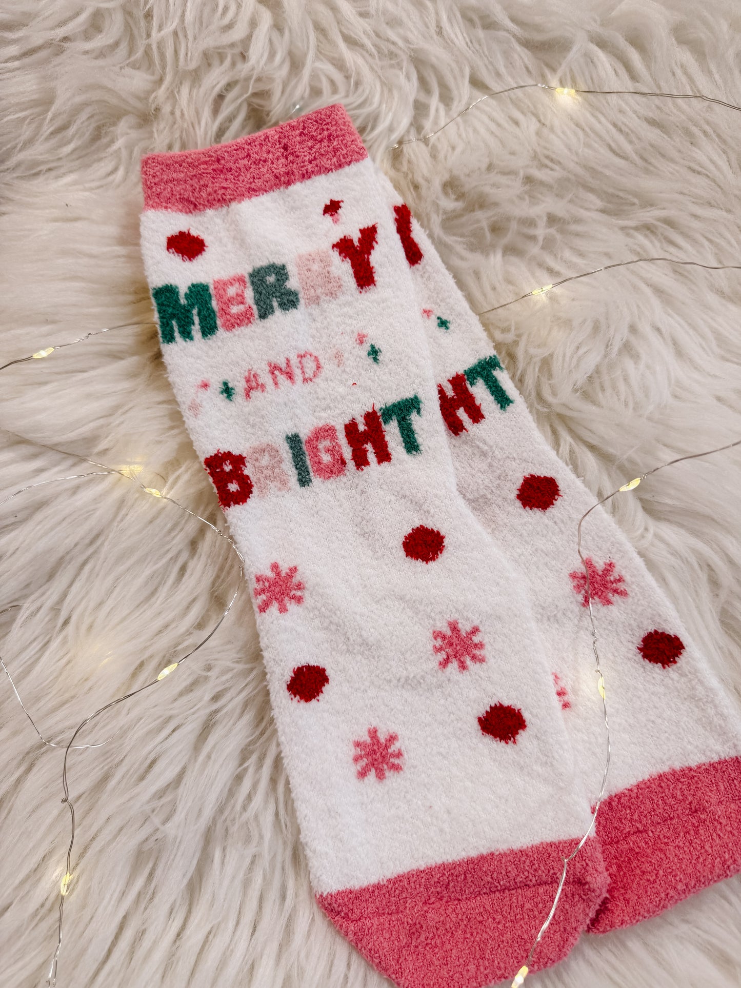 Christmas-themed sock with 'Merry and Bright' text on a fluffy white surface.