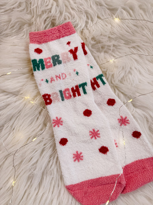 Christmas-themed sock with 'Merry and Bright' text on a fluffy white surface.