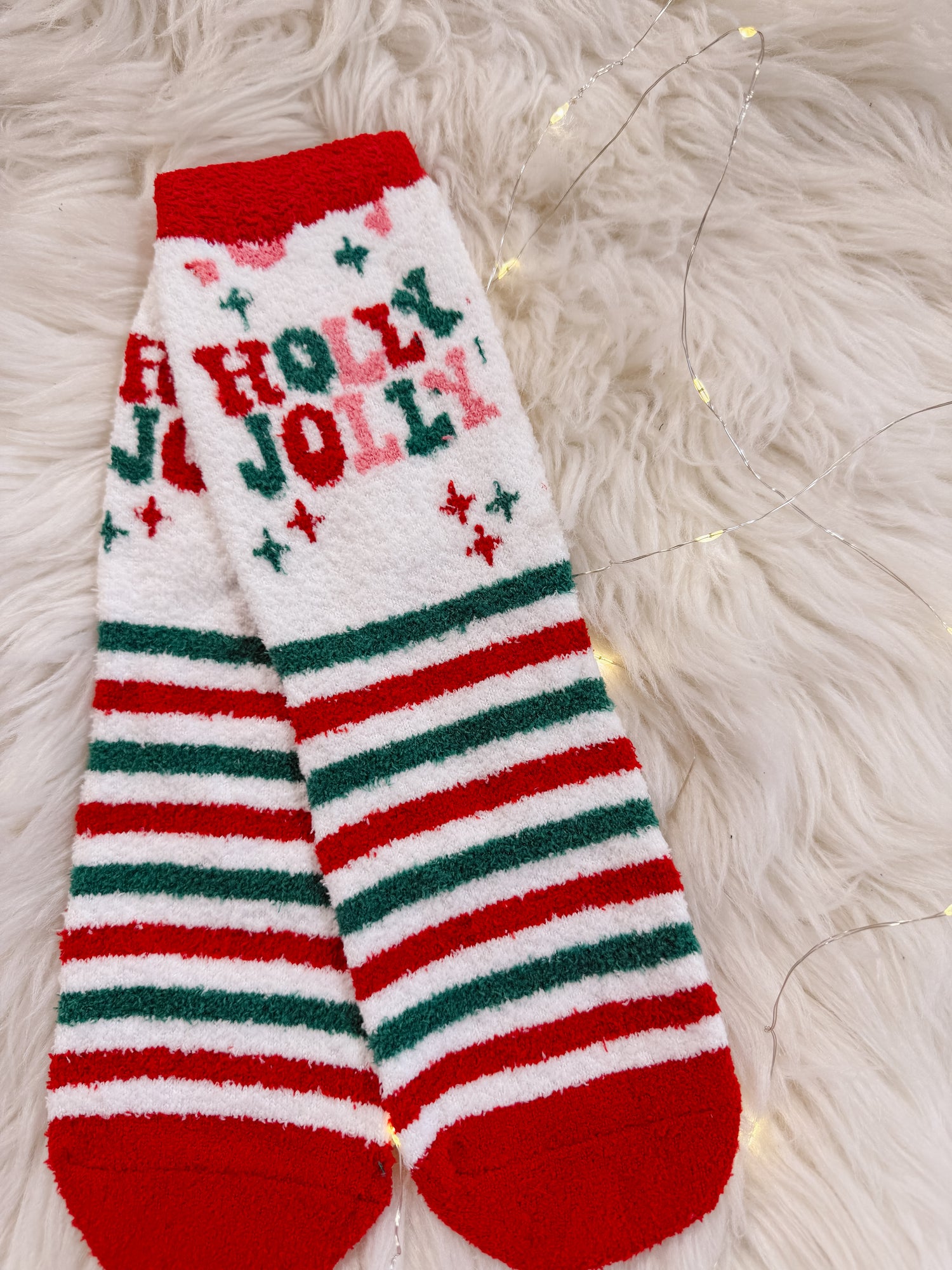 Christmas-themed sock with 'A Holly Jolly' text on a fluffy white surface.