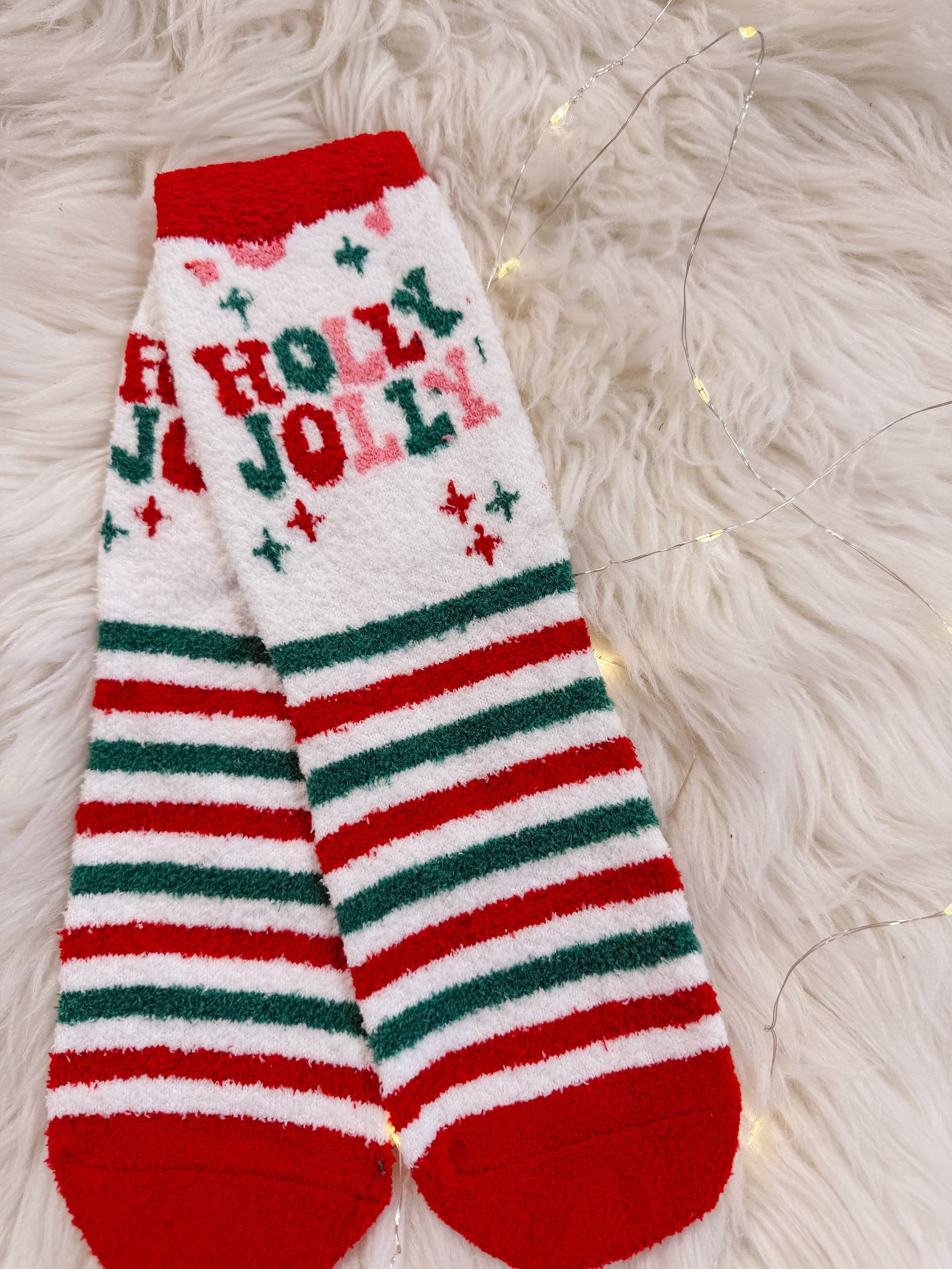 Christmas-themed sock with 'A Holly Jolly' text on a fluffy white surface.