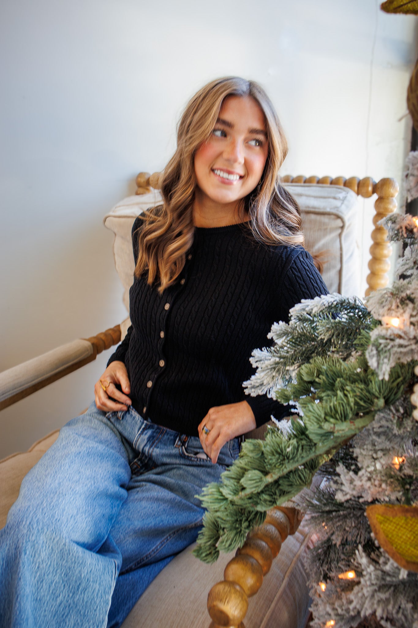 Woman sitting on a chair next to a decorated Christmas tree