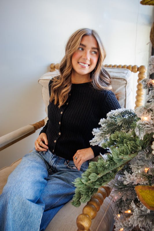 Woman sitting on a chair next to a decorated Christmas tree