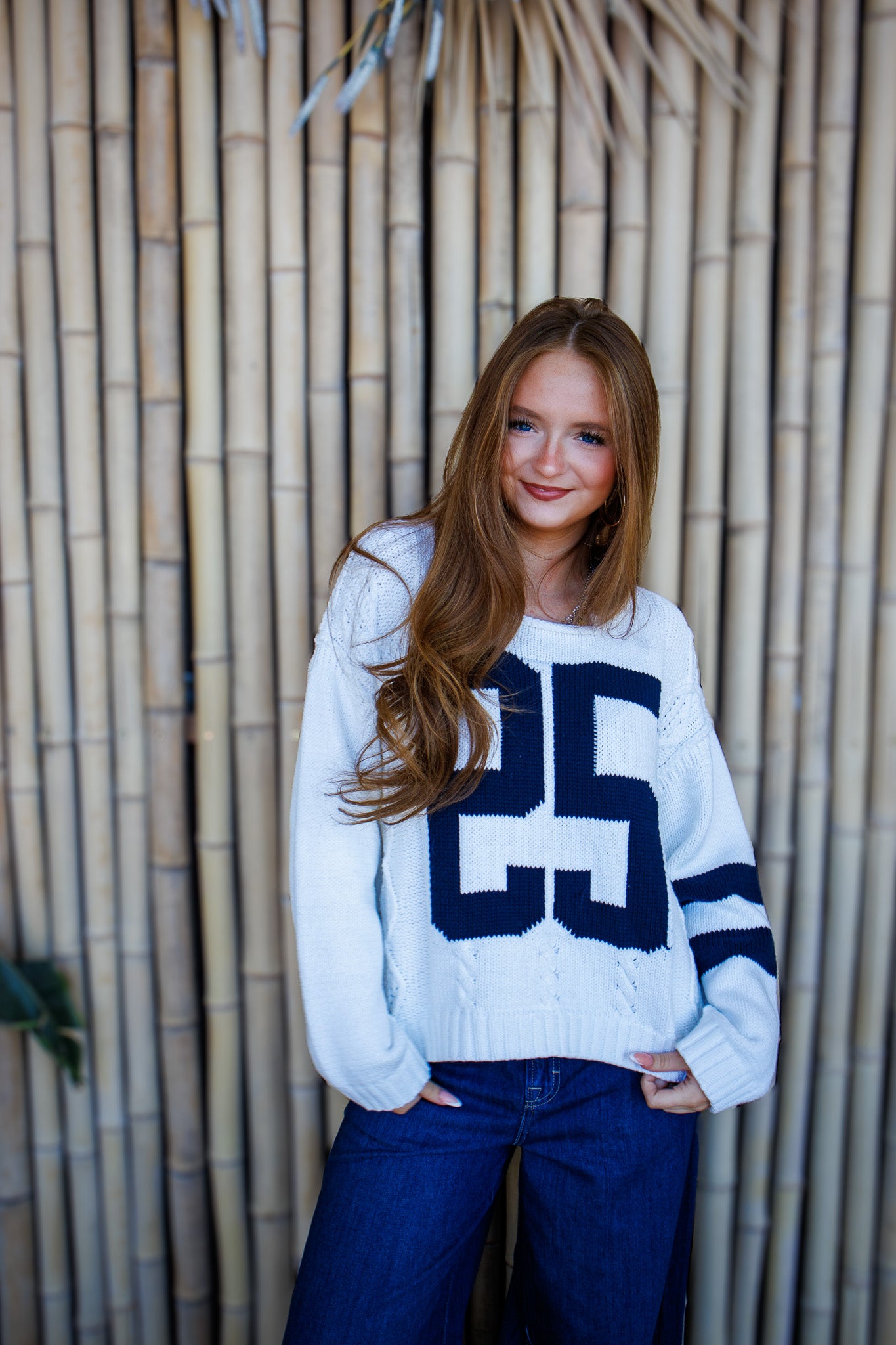 Woman wearing a white sweater with blue numbers against a wooden background