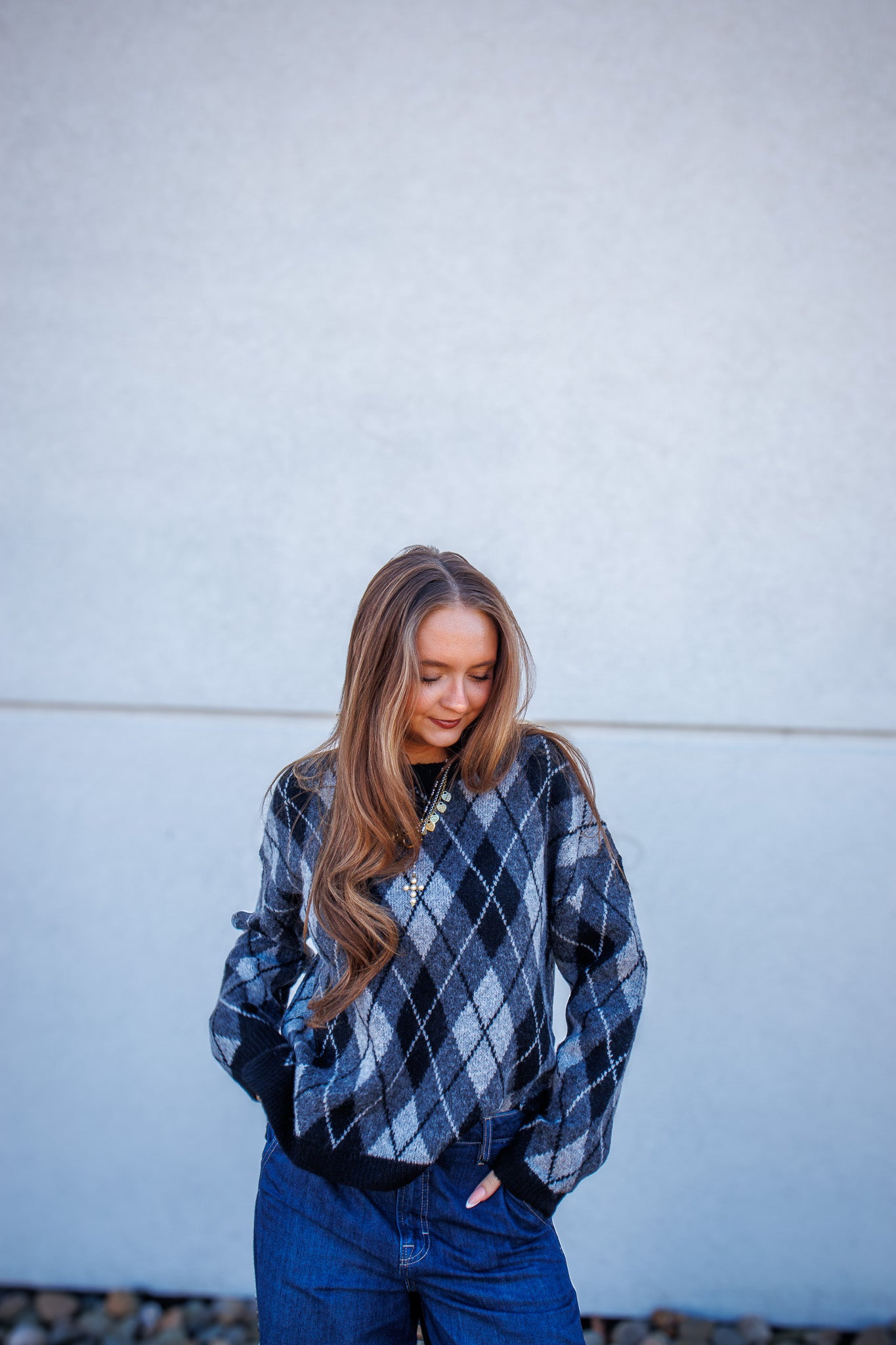 Woman wearing a plaid sweater against a light blue wall