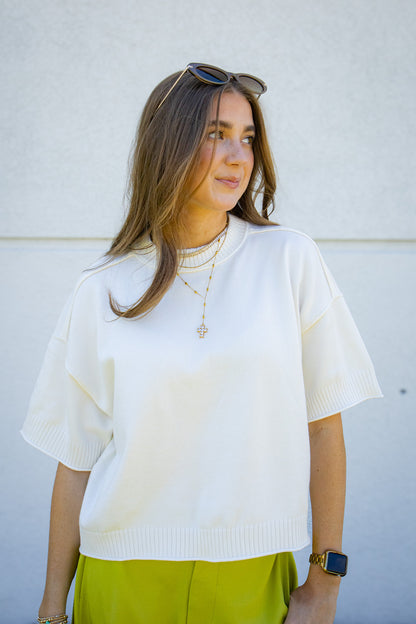 Ivory short sleeve lightweight sweater top with ribbed trim, styled with gold layered necklaces and lime green pants for a fresh summer boutique outfit.