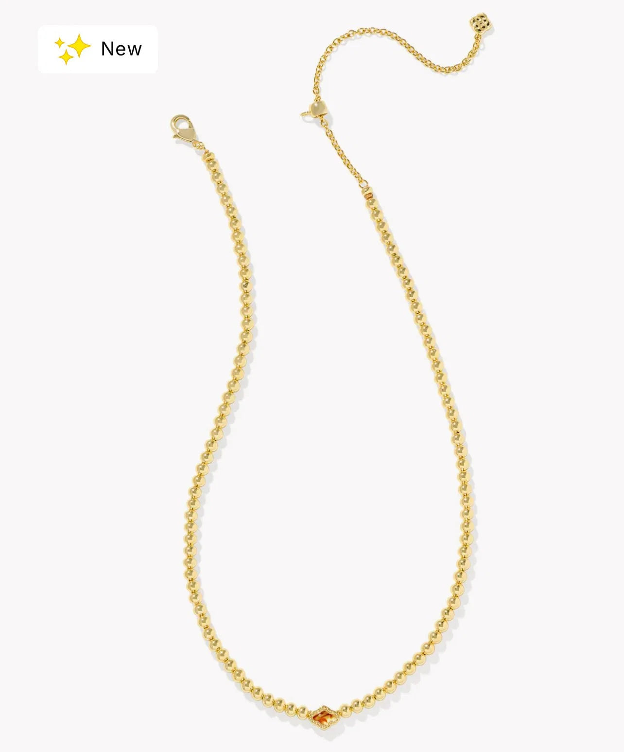 A delicate gold chain necklace with a small central gold bead and a tiny orange gemstone accent, displayed on a clean white background with a 'New' badge in the top-left corner.