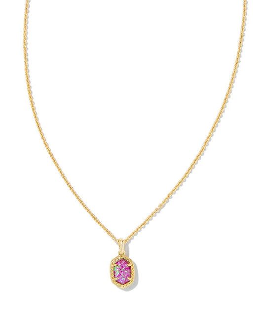 A delicate gold chain necklace featuring a small, irregular-shaped pink gemstone pendant with a textured gold border, set against a plain white background.