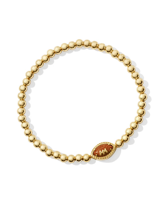 A gold beaded bracelet with a decorative oval charm featuring a red and gold landscape design, displayed on a clean white background.