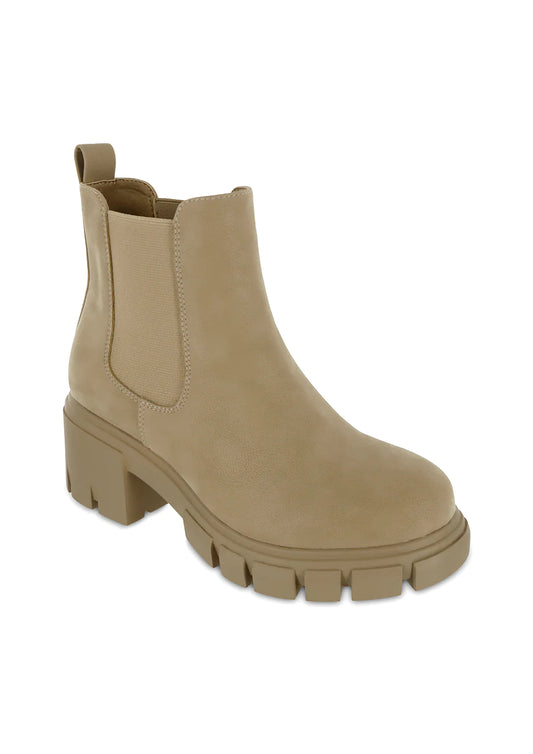 Taupe faux suede Chelsea ankle boot featuring elastic side panels, pull tab, chunky block heel, and an oversized lug sole for a modern everyday fall style.