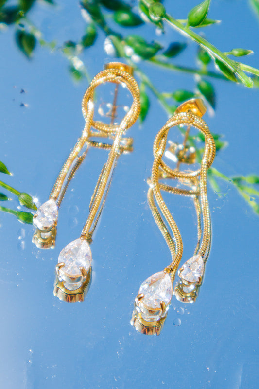 Gold earrings with clear stones on a blue background