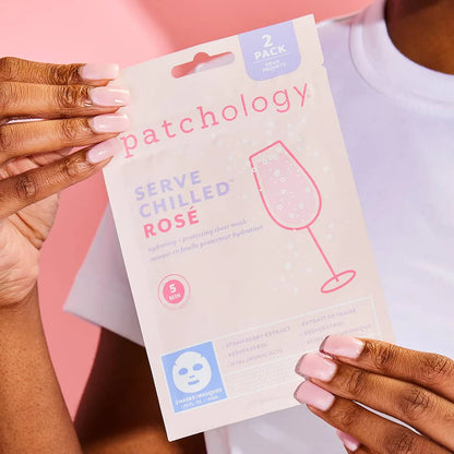 Person holding a 'patchology' face mask package with a pink background