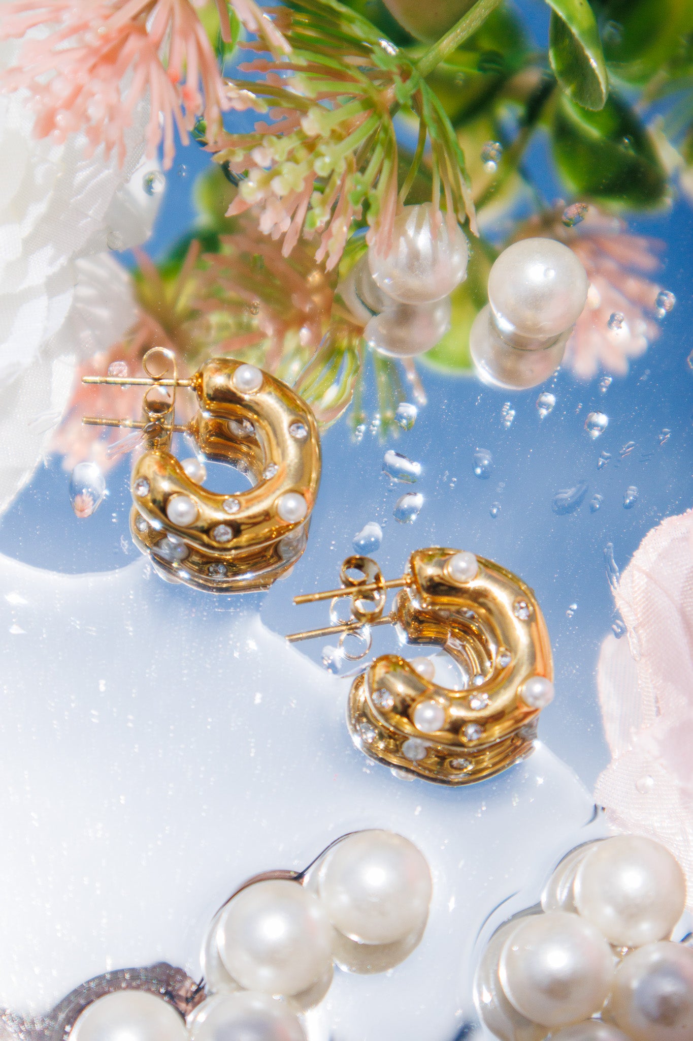 Gold hoop earrings with pearl accents on a floral background