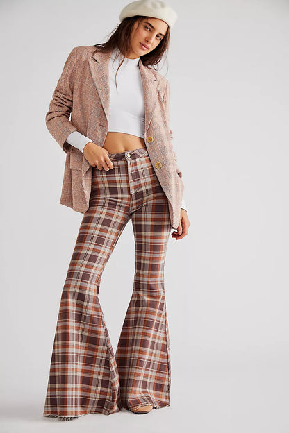 Woman wearing a plaid suit jacket with flared plaid pants on in front of a white background